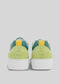 Rear view of N0015 by Jéssica with yellow accents and white soles against a plain background.