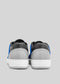 Rear view of M0003 by Luís sneakers with white soles and blue accents on a light gray background.