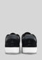 Vista posteriore delle scarpe basse M0001 by Fernando sneakers nere con suola bianca, caratterizzate da tessuto testurizzato e dal logo del marchio sul tallone.