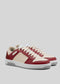 The M0024 by Rodrigo are red and cream sneakers handcrafted in Portugal, featuring white laces and gray soles on a plain gray background.