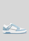 Una sneaker low top bianca e azzurra con perforazioni e suola spessa, su uno sfondo grigio neutro. La M0002 di Sara Q.