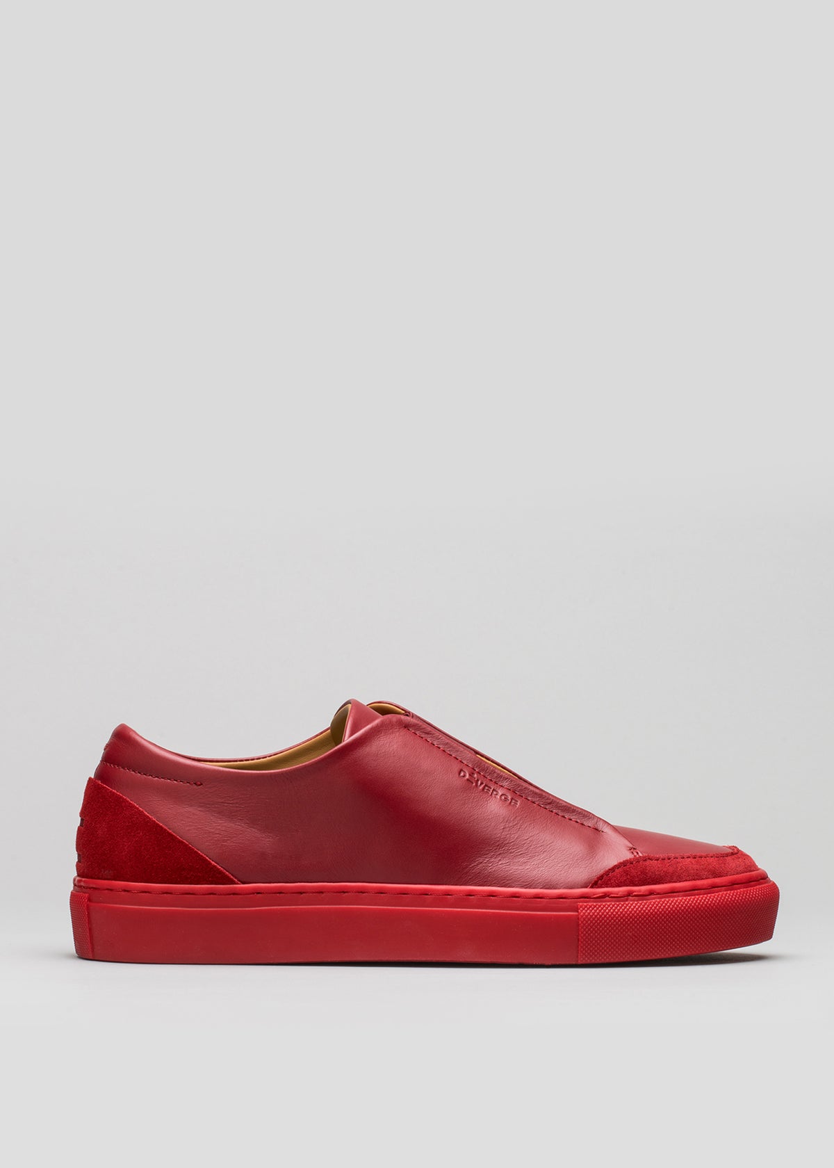 V3 Red Wine Leather è una sneaker slip-on con tomaia testurizzata e suola rossa abbinata, su sfondo neutro.