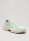 V7 Full Color Sage Green low top sneakers with white laces and a chunky, wavy sole, photographed against a neutral gray background.