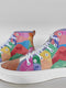 Coloridas zapatillas de lona de caña alta con un diseño de patchwork que muestra varias caras y formas de Smiles sobre un fondo blanco.