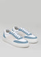 Une paire de V11 White & Artic Blue en daim sneakers avec lacets et semelles blancs, sur fond gris.