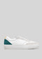 V8 White & Emerald Green low top sneakers with a green heel patch and a small yellow detail, displayed against a gray background.