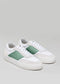 A pair of V12 White & Pastel low-top sneakers with green leather accents and white laces displayed on a gray background.