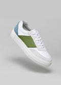 Sneaker bassa V13 White & Pine con pannelli verdi e blu su sfondo grigio.