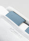Nahaufnahme eines V10 White Leather w/Blue Low-Top-Sneakers, die die strukturierte Lederoberfläche und den Markenaufdruck "deverge" zeigt.