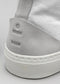 Primer plano de una zapatilla alta gris TH0011 by Joana que muestra el logotipo en relieve en el talón y la suela blanca texturizada.