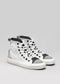 Un par de zapatillas TH0011 by Joana sneakers con puntera y cordones negros, sobre fondo gris claro.