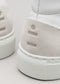 Gros plan sur les talons arrière des chaussures montantes V8 White Leather w/Bone sneakers avec le mot "fine" embossé en gris sur un patch texturé.