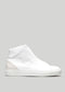 Empieza con unas zapatillas de piel de caña alta de lona blanca sobre fondo gris, con un diseño minimalista y un sutil detalle de la marca en el lateral.
