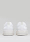 Vue arrière d'une paire de chaussures vegan en toile blanche à semelles épaisses sur fond gris clair.