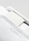 Nahaufnahme eines Start mit einem Slip-on-Sneaker aus weißem Canvas mit strukturierter Oberfläche und einem Riemen, auf dem der Markenname "deverge" eingeprägt ist.