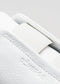 Primo piano di un Slip On White Canvas che mostra la pelle testurizzata e il cinturino in velcro con il logo "deverge" in rilievo.