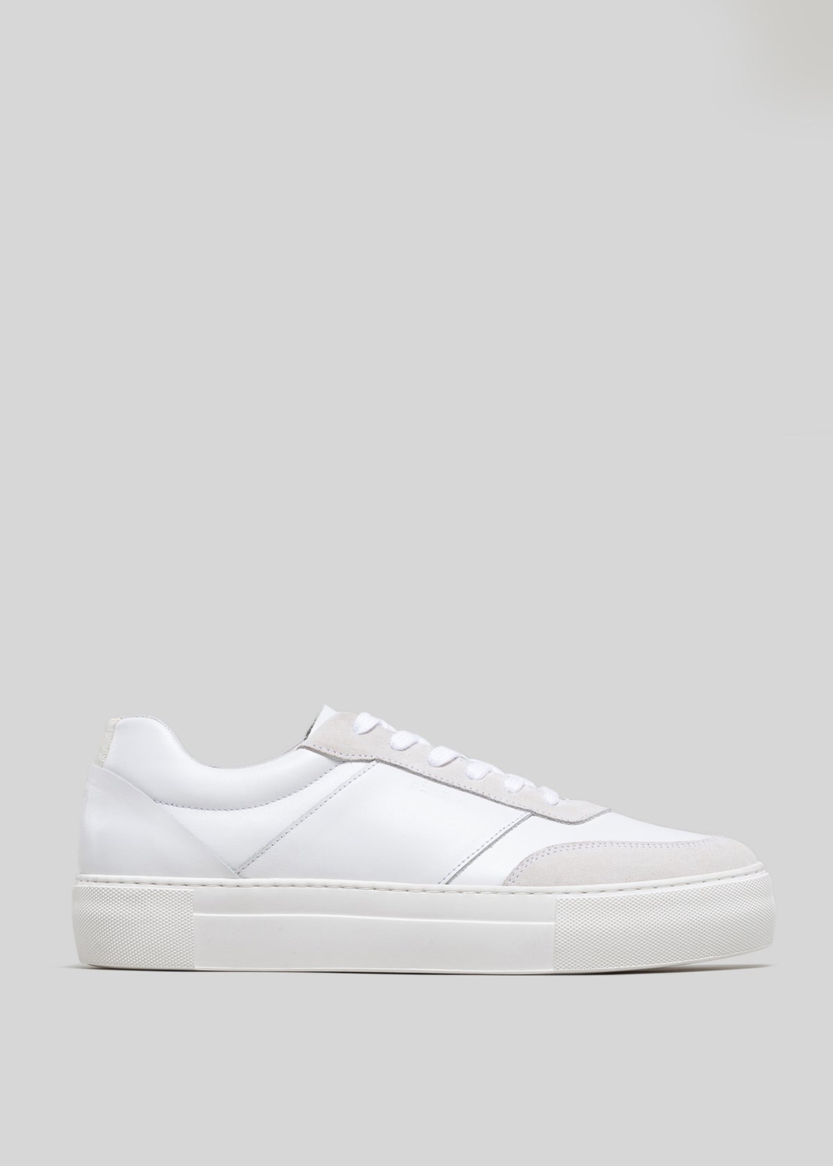 A side view of a Start with a White Canvas, low-top sneaker with a flat sole and white laces against a grey background.