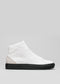 V32 Vegan White W/Beige high-top sneakers con suola nera e design minimalista su sfondo grigio.