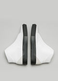Un paio di V32 Vegan White W/Beige high top sneakers con dettagli di cerniera neri su sfondo grigio.