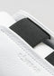 Detalle de la V6 de piel blanca con negro sneakers con detalles texturizados y un lazo de tela negra, con el nombre de la marca "deverge" en relieve.