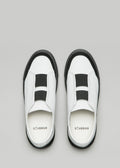 Ein Paar V6 White Leather w/Black slip-on sneakers mit schwarzen Gummibändern, von oben gesehen auf grauem Hintergrund.