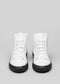 A pair of V1 White Leather w/Bone high-top sneakers with black soles, displayed against a gray background.