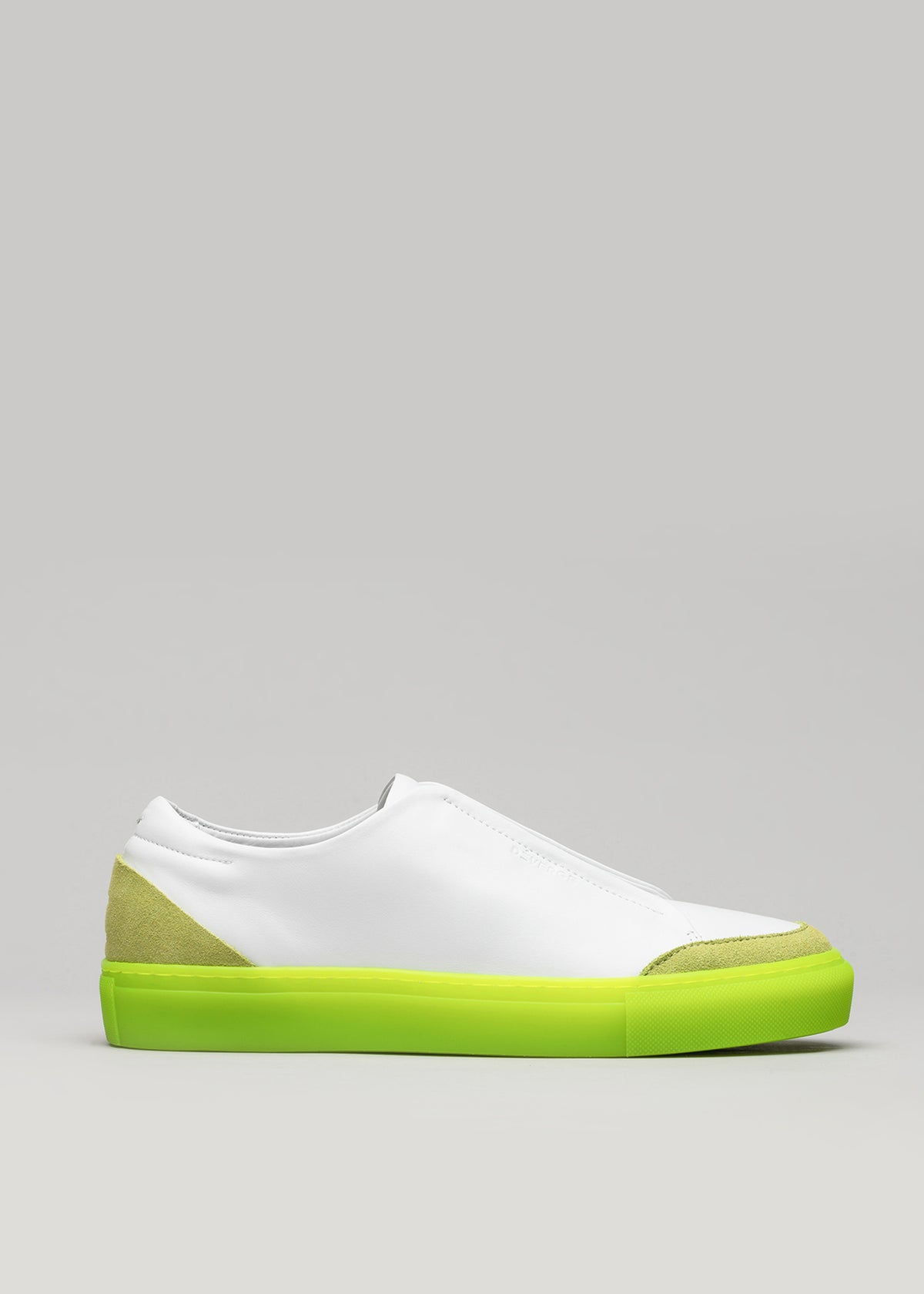 A V9 White Leather w/Lime slip-on sneaker with a neon green sole and a light green suede detail on the heel, displayed against a gray background.